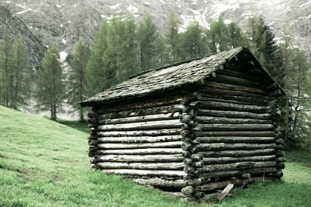 An aged log cabin showcasing the intricate crisscross pattern of weathered logs, each bearing the marks of time and history.